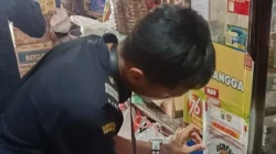 Petugas Bea Cukai menempelkan stiker gempur rokok ilegal di toko-toko. [TanyaFakta.id/HO-Bea Cukai Jambi]