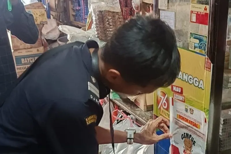 Petugas Bea Cukai menempelkan stiker gempur rokok ilegal di toko-toko. [TanyaFakta.id/HO-Bea Cukai Jambi]